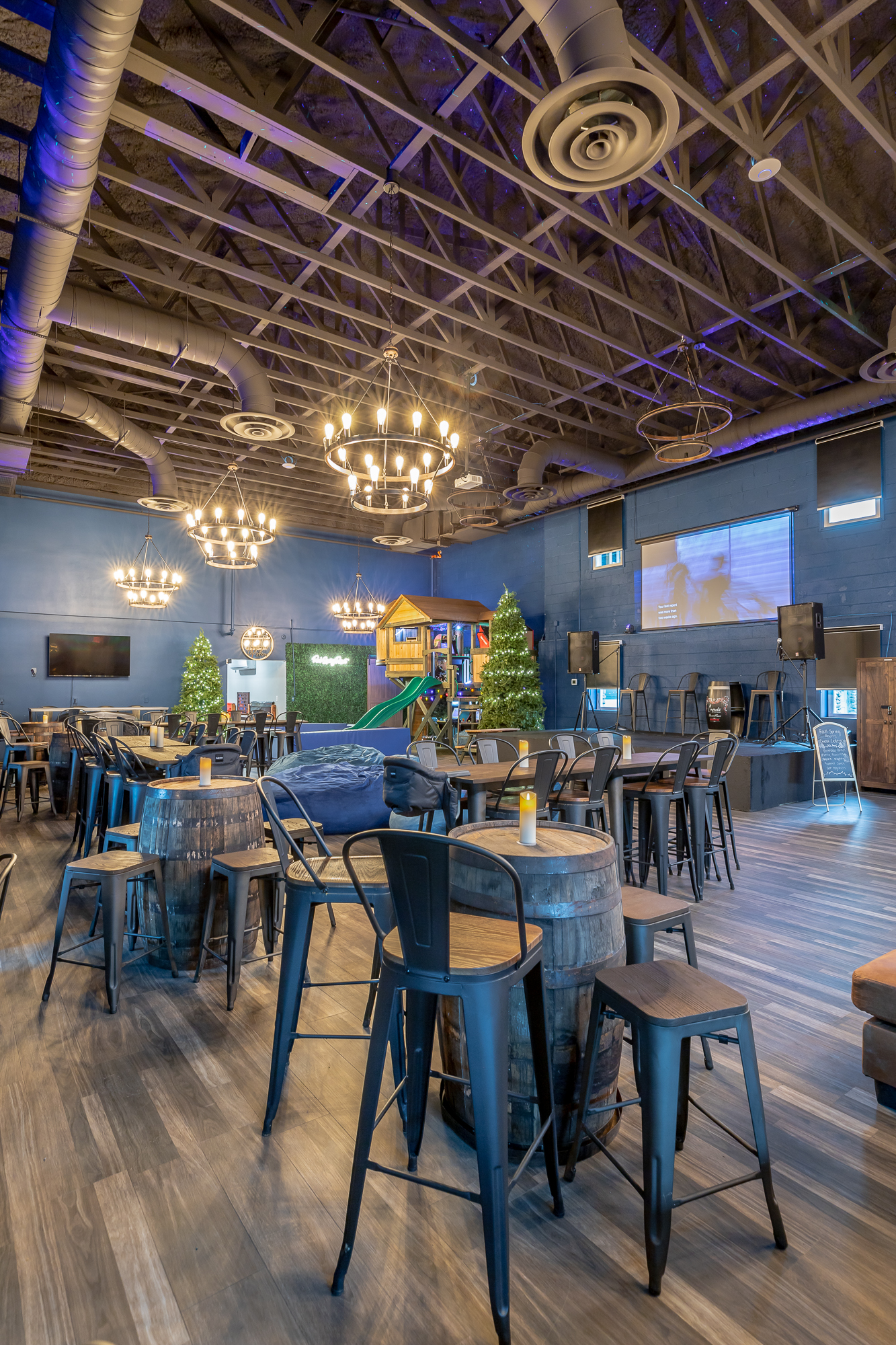 Wide-angle view of Rock Spring Resort event center showing the stage, bean bags, seating area, and treehouse with ball pit and slide in background.