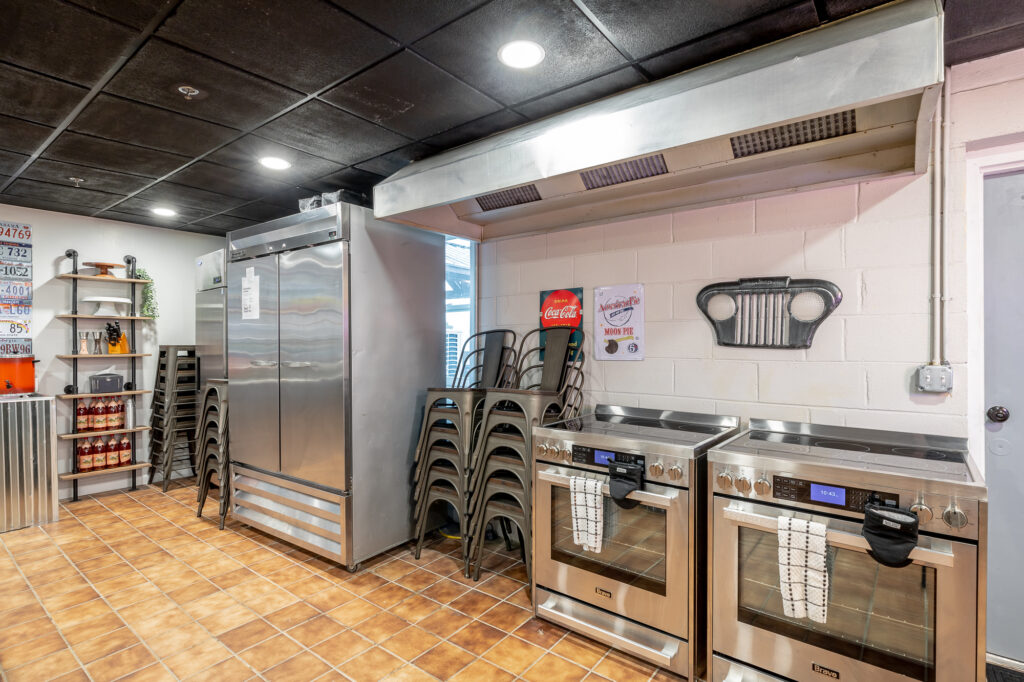 Partial view of Rock Spring Resort's event center kitchen with double ovens, commercial refrigerator, and extra chairs for guests.